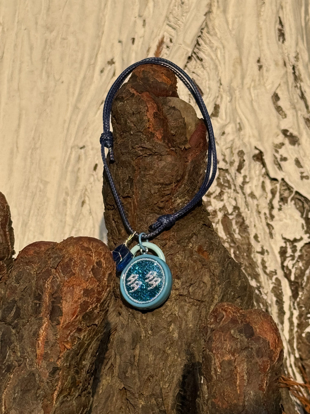 Blue pet necklace with a round dog/cat name id tag in acrylic on a textured wooden surface
