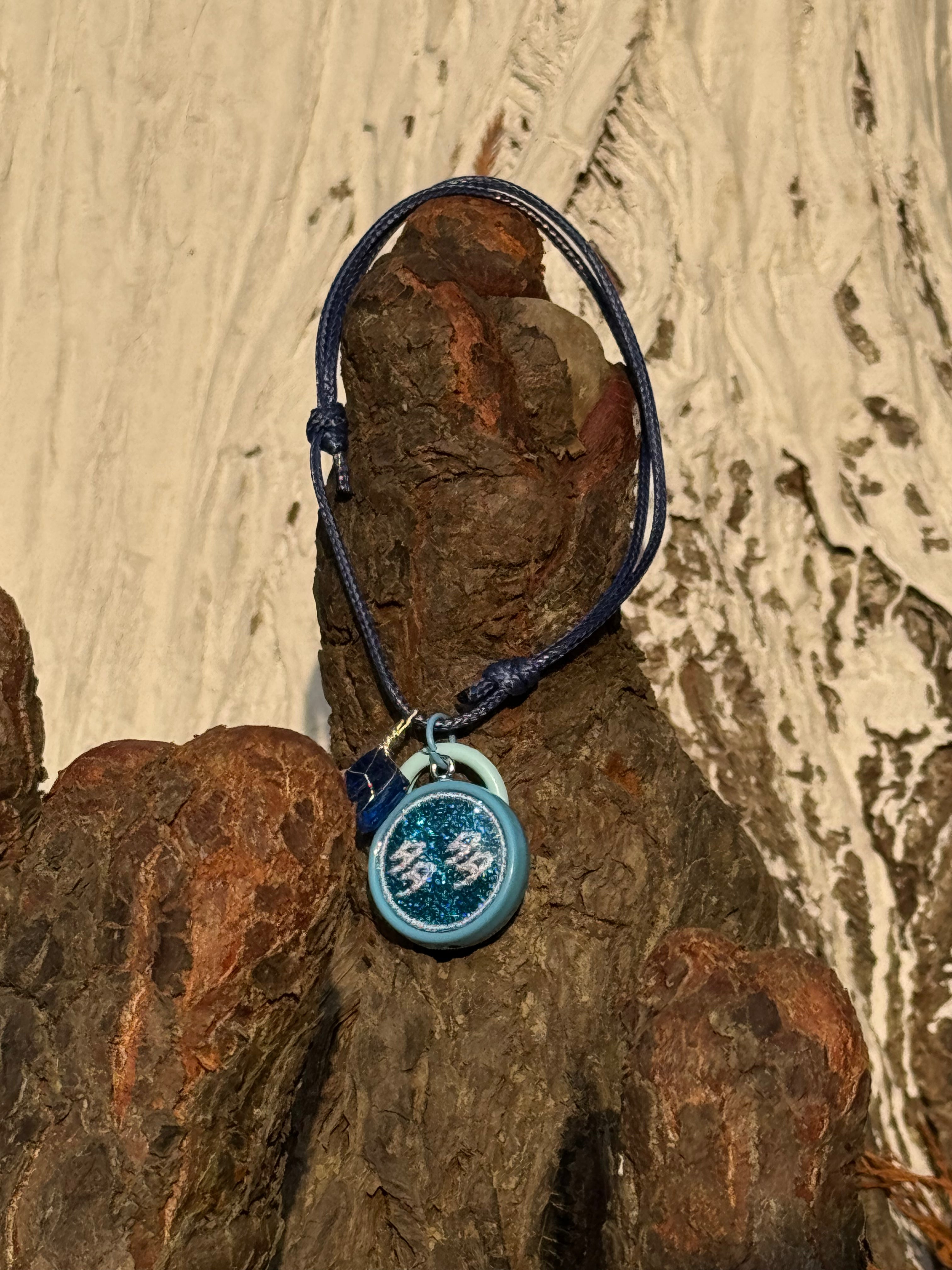 Blue pet necklace with a round dog/cat name id tag in acrylic on a textured wooden surface