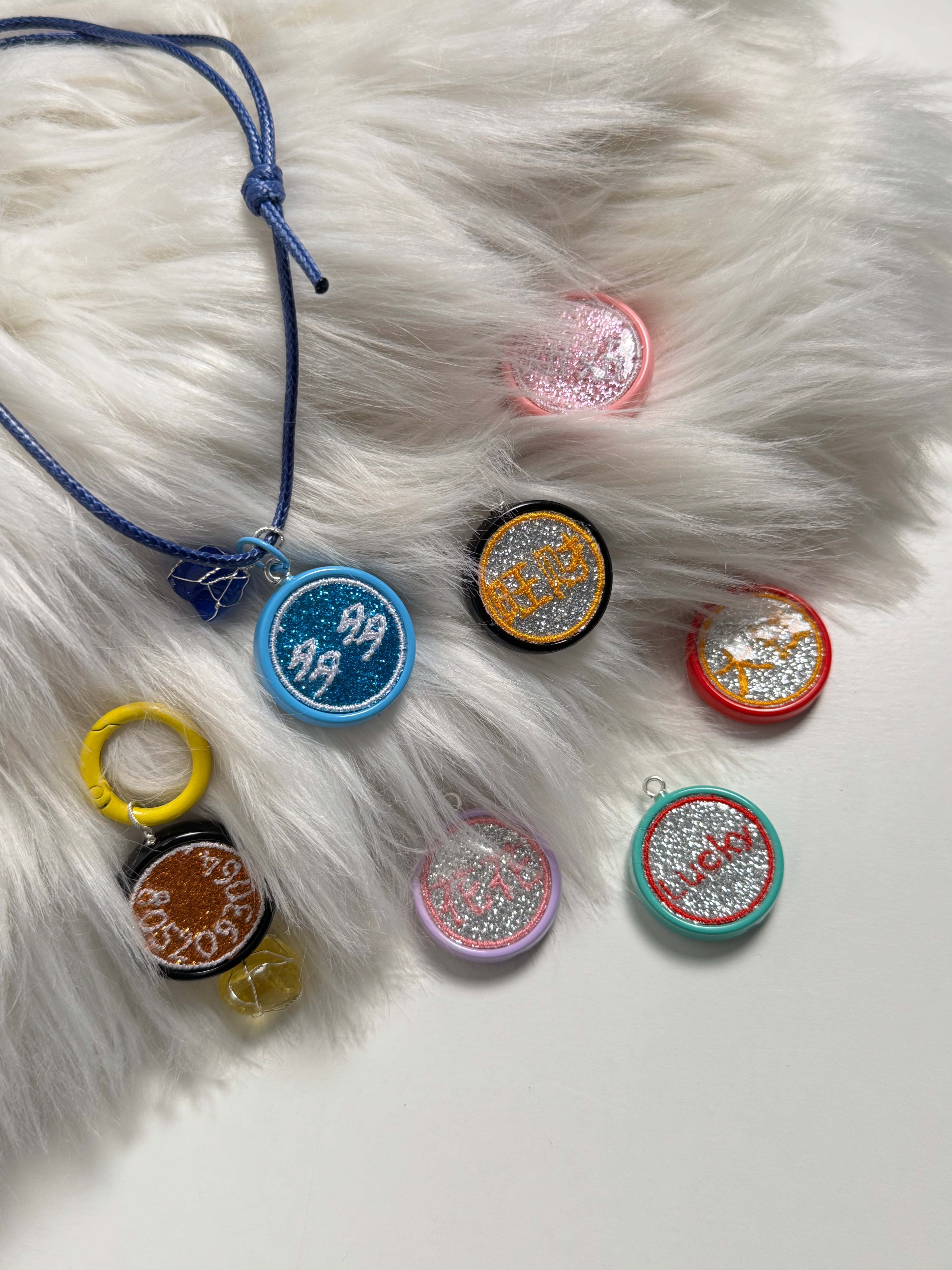 Colorful round glitter pet id pedant in acrylic on a blue cord on a white fur surface