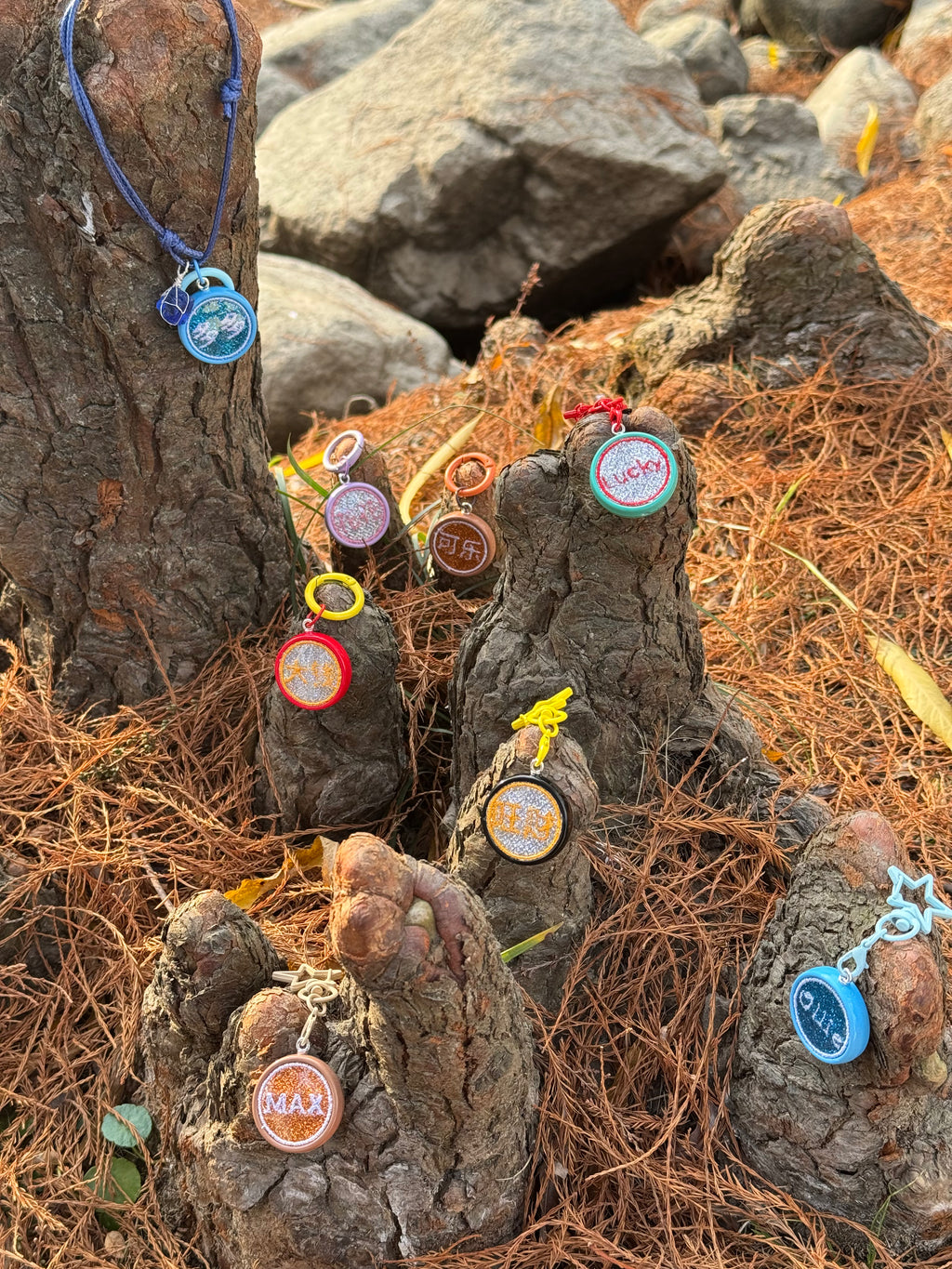 Decorative stone statues with colorful tags on a natural setting with rocks and straw.