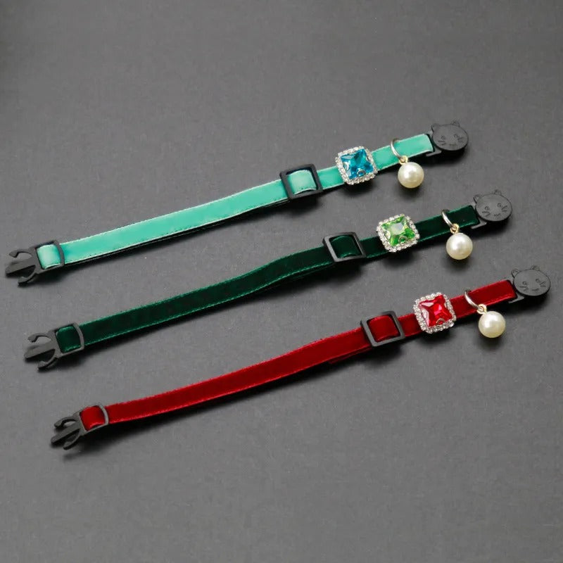 Three colorful cat collars with decorative elements on a gray background